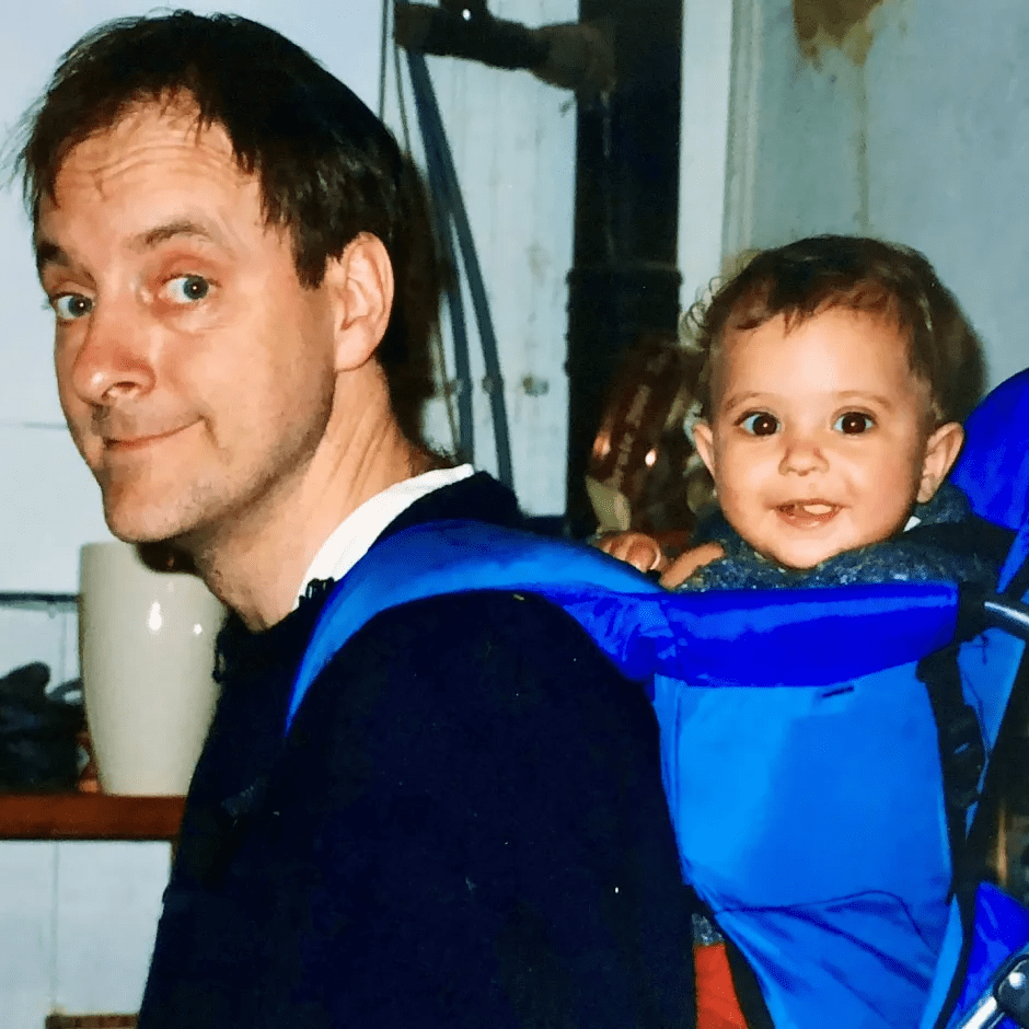 A man carrying a baby in a blue carrier.