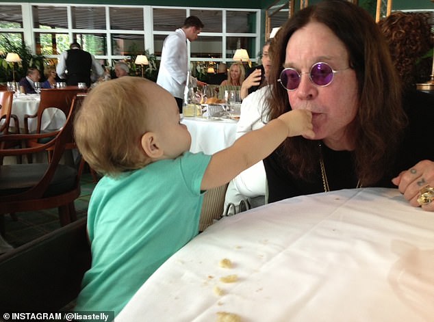 The heavy metal icon proved to be a good sport in another photo in which he let one of his baby granddaughters stick her fingers in his mouth