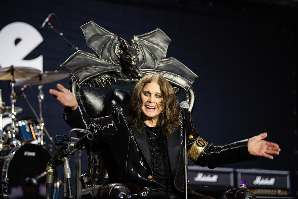 Screenshot of a performer on stage singing into a microphone while sitting on a throne.