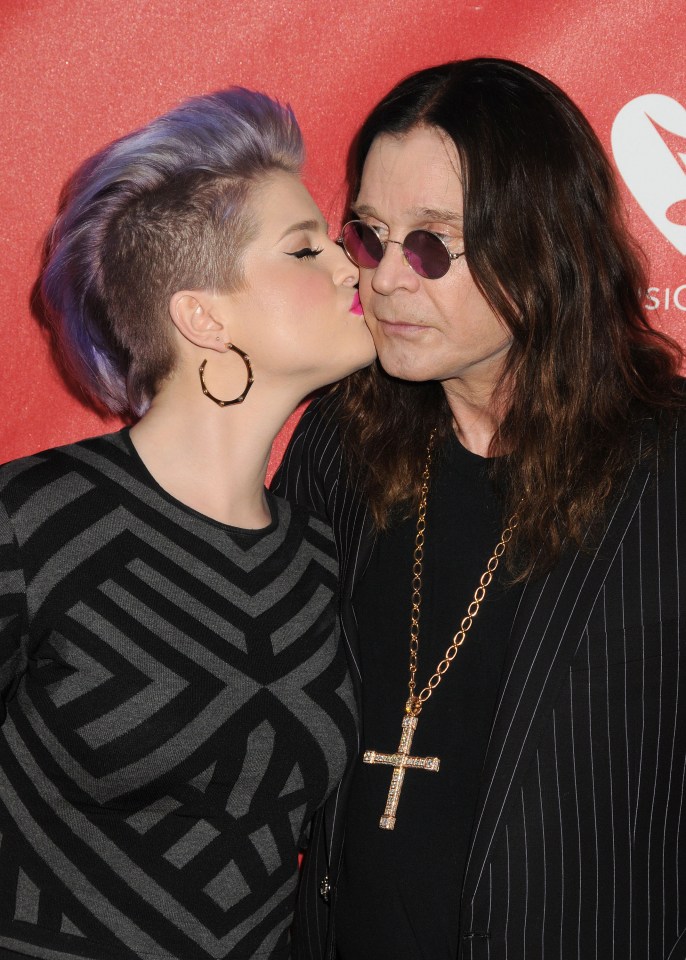 Kelly Osbourne kissing Ozzy Osbourne on the cheek.
