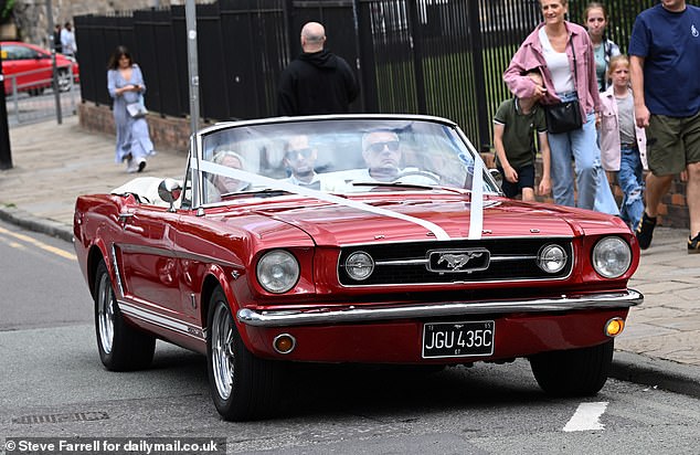 The Coronation Street actor cut a dapper figure in a white suit as he arrived in a red mustang with his mum and son
