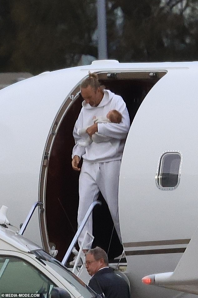 Justin looked like the proud dad as he carefully carried his one-month-old baby while making his way down the stairs of the jet