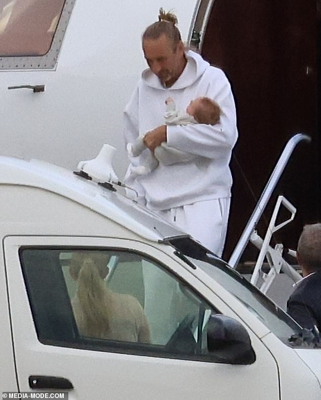 He kept comfy for the flight in a white oversized hoodie and matching tracksuit pants