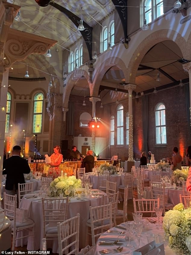 Guests enjoyed their meal in a stunning high-ceiling venue featuring arches and stained glass windows, with beautiful white flower bouquets on each table