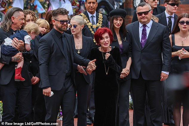 Jack Osbourne holds mother Sharon's hands as the procession travelled through Birmingham