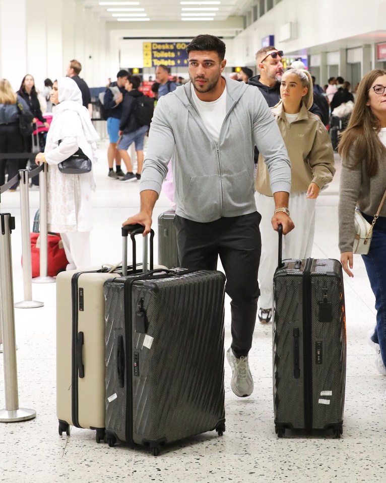 Molly-Mae Hague and Tommy Fury at Manchester Airport with luggage.
