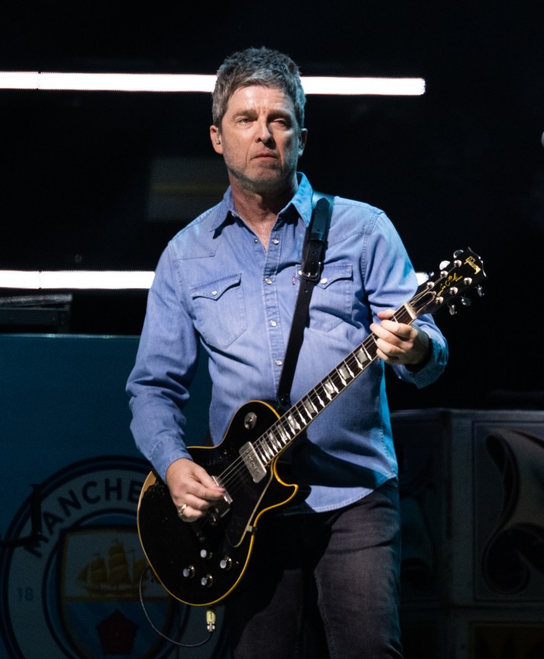 Noel Gallagher of Oasis playing guitar on stage.