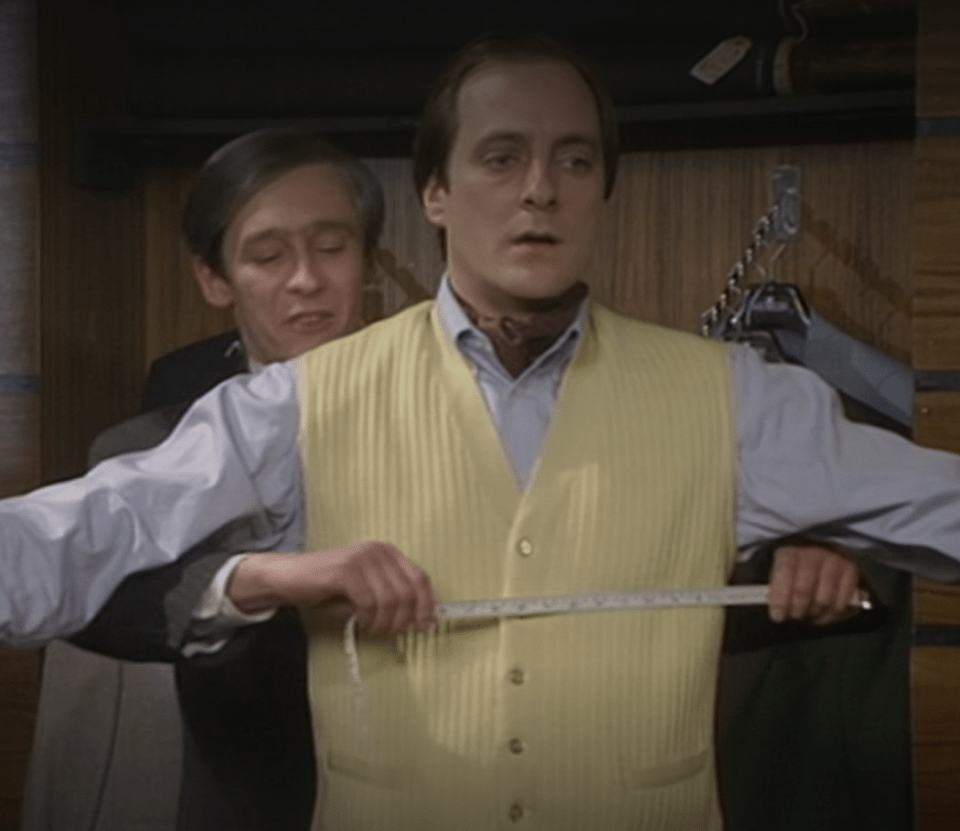A man having his vest measured by a tailor.