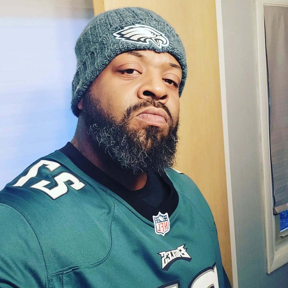 Man wearing a Philadelphia Eagles jersey and knit cap.