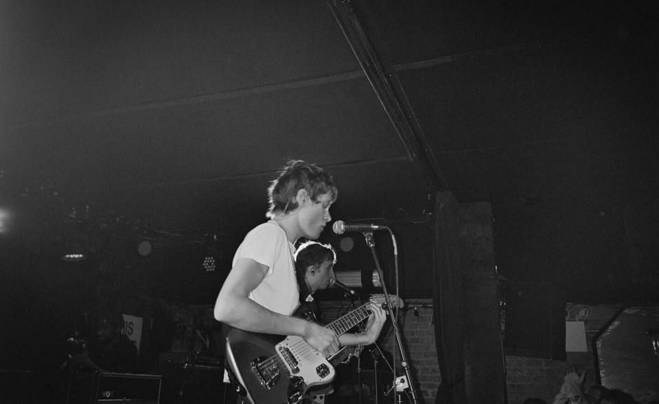Black and white photo of Moses Martin playing guitar on stage.