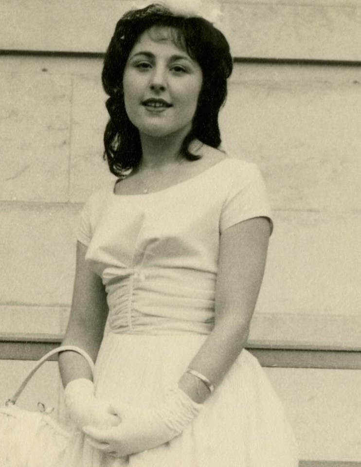 Black and white photo of a young woman in a light-colored dress and gloves.