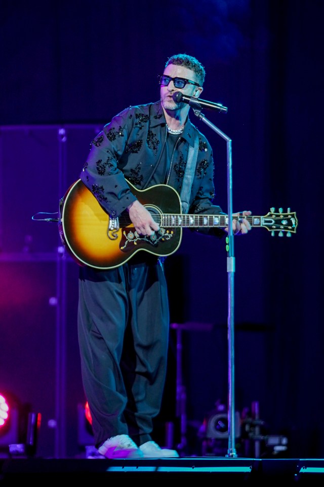 Justin Timberlake performing on stage with an acoustic guitar.
