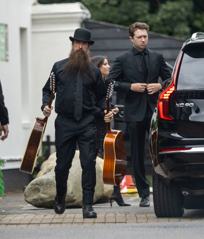 Zakk Wylde carrying two guitars, leaving a memorial service.