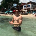 A Hollywood star's nepo baby son revealed his ripped torso and bulging biceps while on holiday with his stunning girlfriend on Instagram on Friday - but can you guess who is famous father is?
