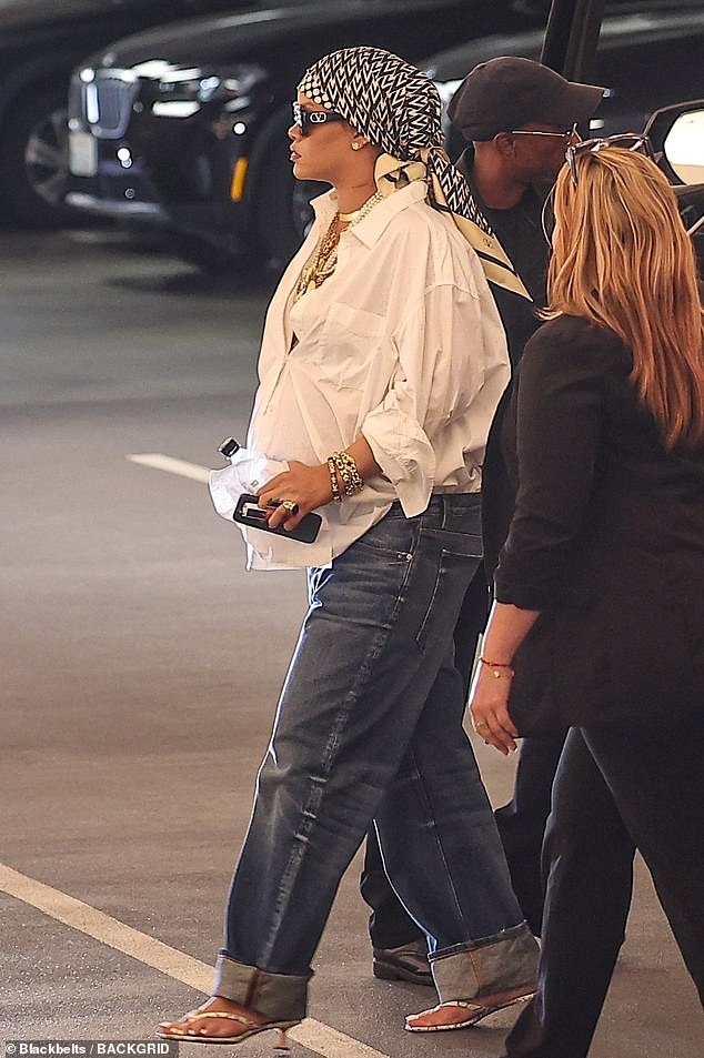 Pregnant Rihanna covered up her growing baby bump with a white button-up shirt and jeans while running errands in Beverly Hills on Friday